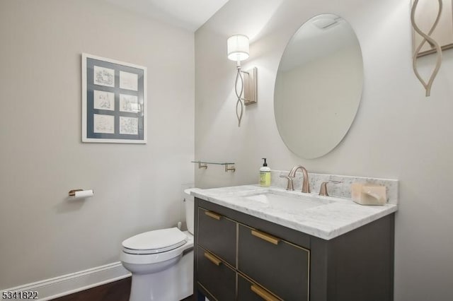 bathroom featuring toilet, baseboards, and vanity