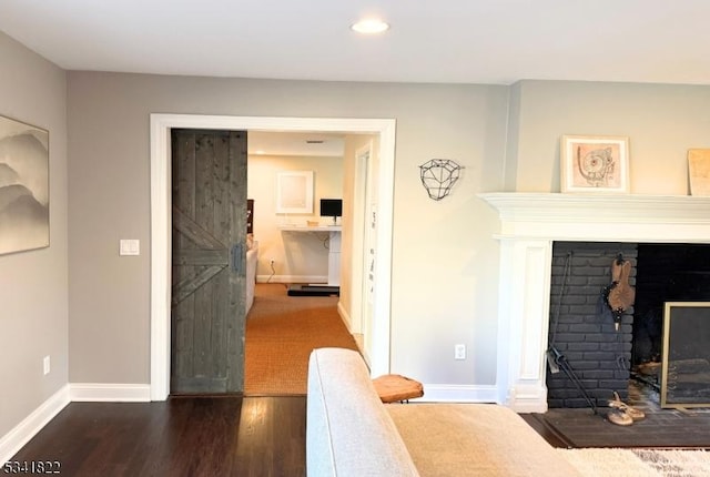 living room featuring dark wood-type flooring, a fireplace, recessed lighting, and baseboards