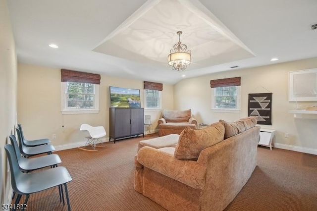 living area featuring a tray ceiling, carpet, and baseboards