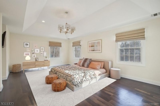 bedroom with multiple windows, baseboards, a raised ceiling, and wood finished floors