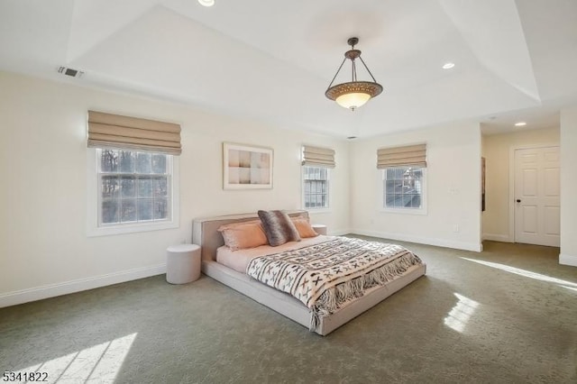 carpeted bedroom with a tray ceiling, recessed lighting, visible vents, and baseboards