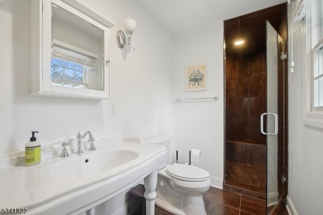 full bathroom with baseboards, a sink, a shower stall, and toilet