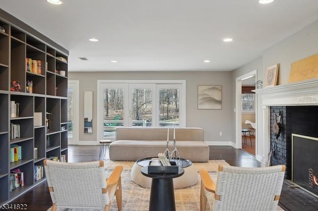 living area with a lit fireplace, baseboards, wood finished floors, and recessed lighting