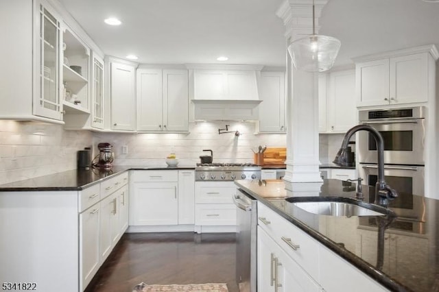 kitchen featuring premium range hood, a sink, white cabinetry, appliances with stainless steel finishes, and dark stone countertops