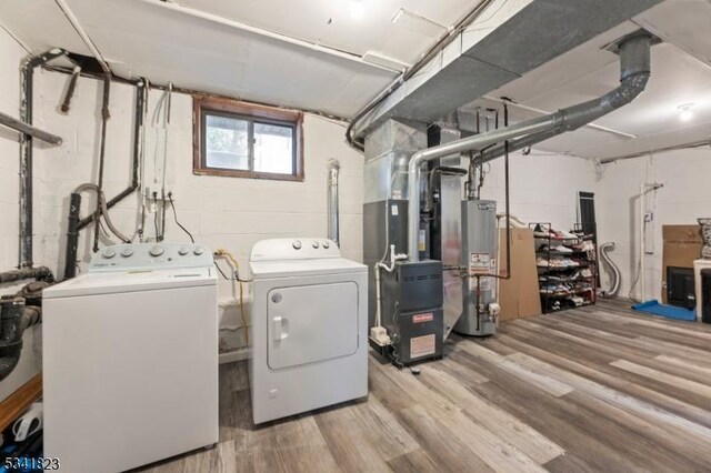 clothes washing area with washing machine and clothes dryer, laundry area, gas water heater, and wood finished floors