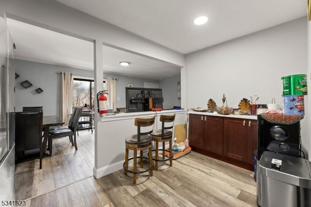 kitchen featuring light wood-type flooring, baseboards, dark brown cabinets, and light countertops