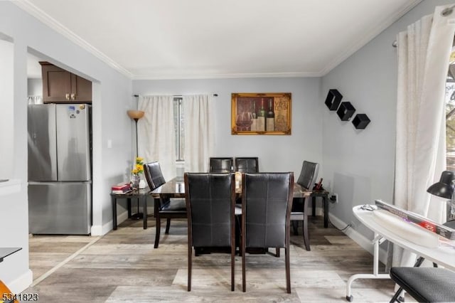 dining space featuring baseboards, light wood-style floors, and ornamental molding