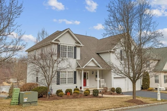 traditional-style home featuring a garage, driveway, and roof with shingles