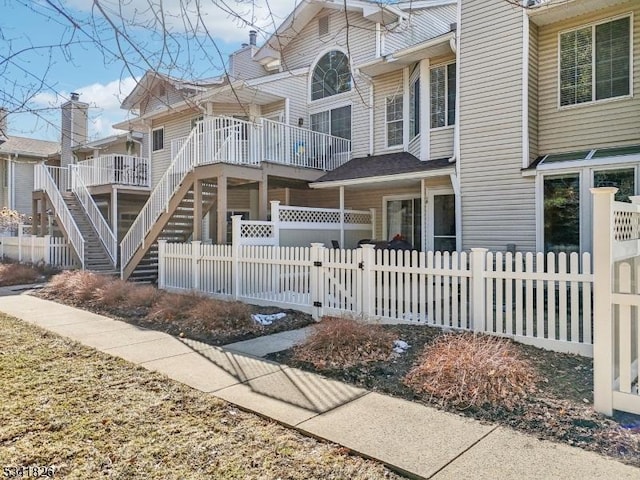 view of front facade with stairs, a fenced front yard, and a chimney