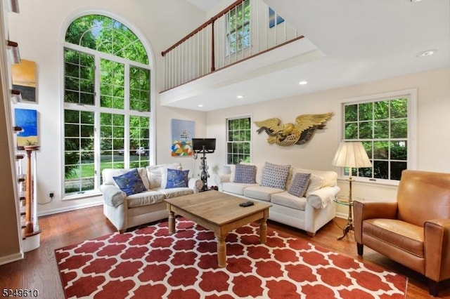 living room with recessed lighting, plenty of natural light, a high ceiling, and wood finished floors