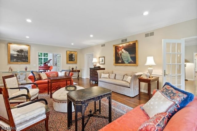 living area with recessed lighting, visible vents, crown molding, and wood finished floors