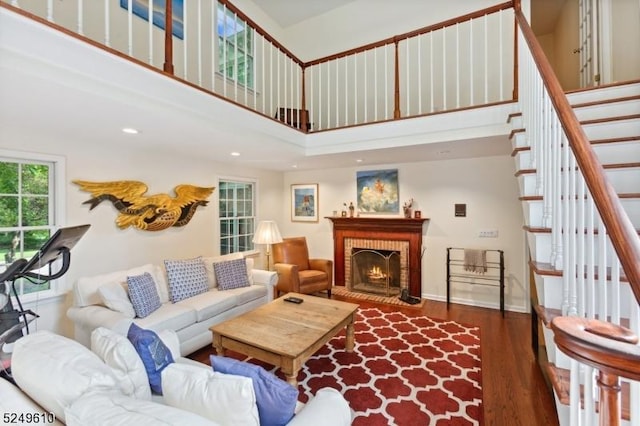 living room featuring baseboards, wood finished floors, stairs, a fireplace, and recessed lighting