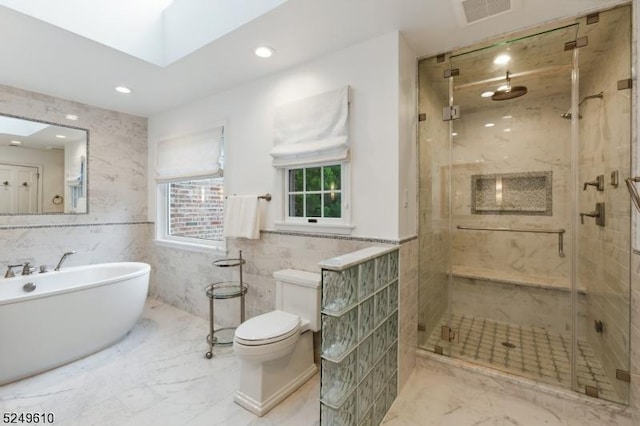 full bathroom with a skylight, visible vents, tile walls, marble finish floor, and a stall shower