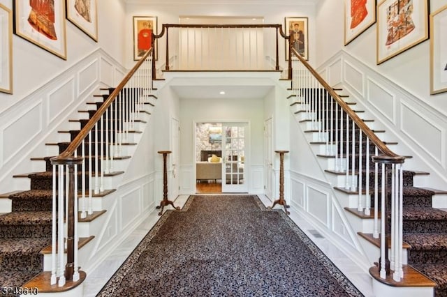 foyer featuring a high ceiling, stairway, and a decorative wall