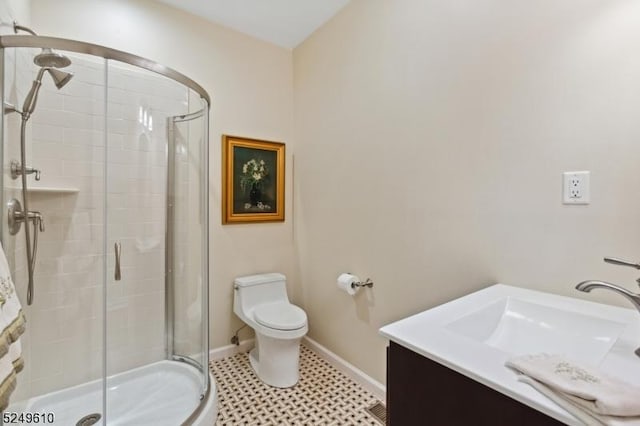 bathroom with a stall shower, toilet, vanity, and baseboards