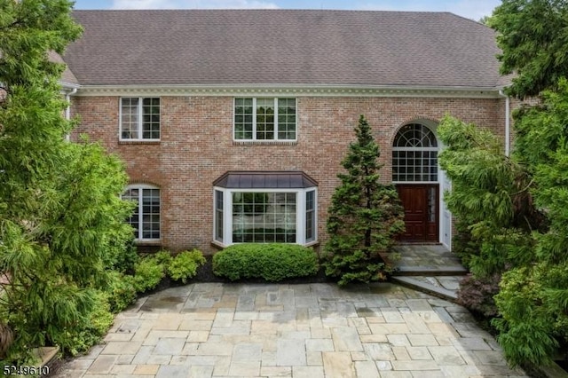 colonial home with brick siding and roof with shingles