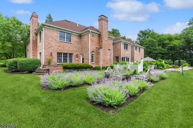 back of property with brick siding, a lawn, and a chimney