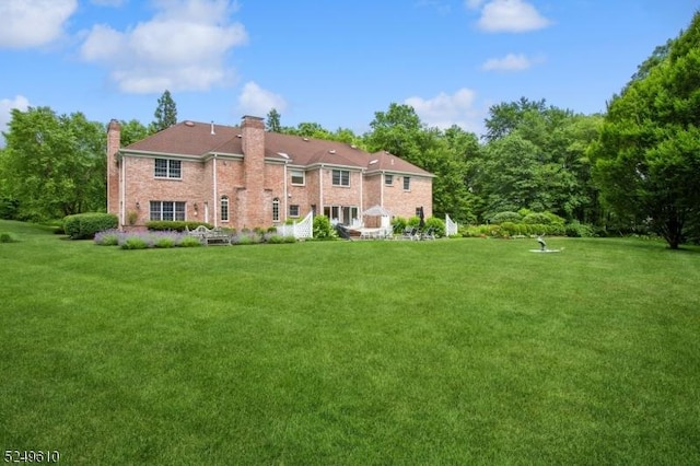 rear view of property featuring a chimney and a lawn