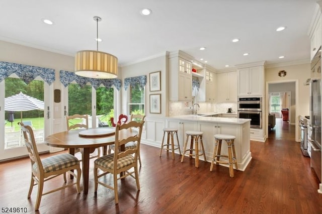 dining room featuring ornamental molding, a decorative wall, dark wood-style flooring, and recessed lighting