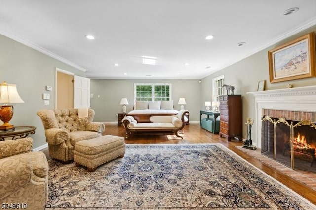 living room with ornamental molding, a brick fireplace, wood finished floors, and baseboards