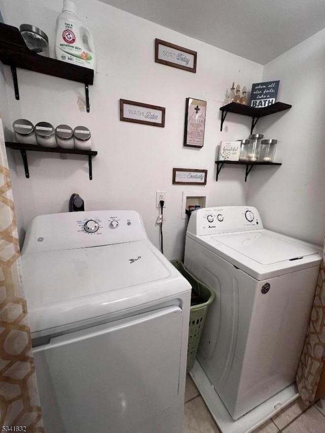 clothes washing area featuring laundry area, light tile patterned floors, and washer and clothes dryer