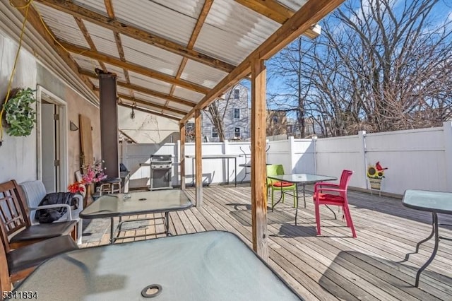 wooden terrace featuring a grill, a fenced backyard, and outdoor dining space