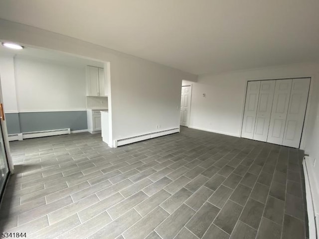 interior space featuring a baseboard radiator, baseboards, and wood finished floors