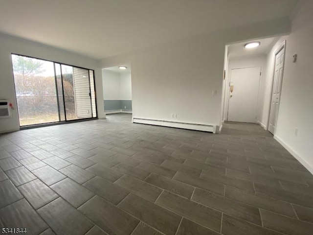 spare room featuring a baseboard heating unit, wood finish floors, and baseboards