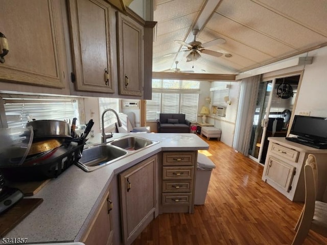 kitchen featuring lofted ceiling with beams, light countertops, a peninsula, wood finished floors, and a sink