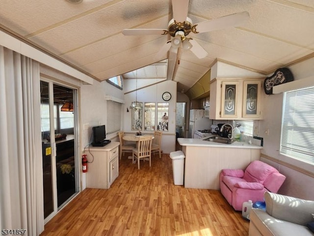 kitchen featuring light wood finished floors, a sink, light countertops, and vaulted ceiling