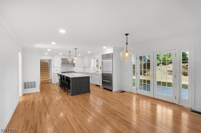 kitchen with visible vents, stainless steel built in refrigerator, light countertops, under cabinet range hood, and white cabinetry