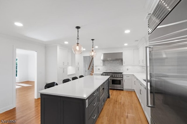 kitchen with range hood, high end appliances, light countertops, light wood-style floors, and white cabinetry