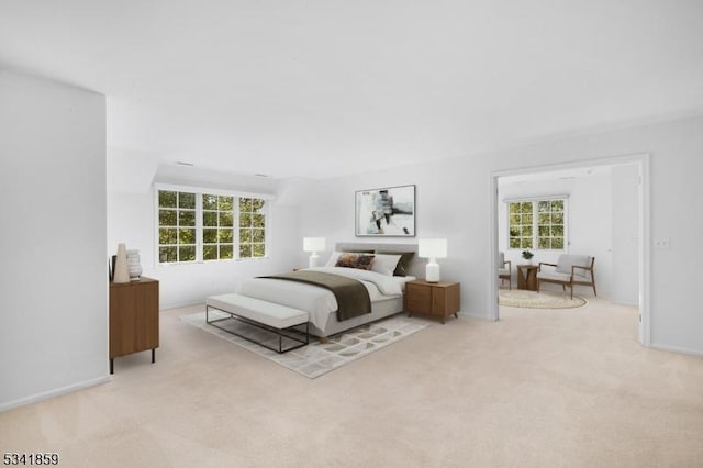 bedroom featuring light carpet, multiple windows, and baseboards