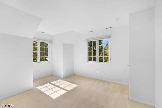 empty room with carpet, visible vents, and baseboards