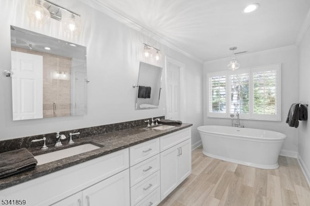 bathroom featuring a freestanding tub, ornamental molding, a sink, and wood finished floors