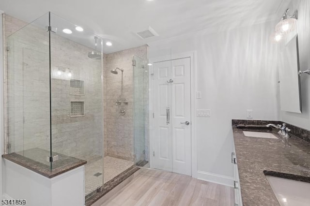 full bathroom featuring a stall shower, baseboards, a sink, and wood finished floors