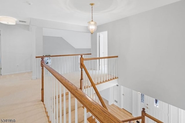 corridor featuring visible vents, carpet flooring, and an upstairs landing