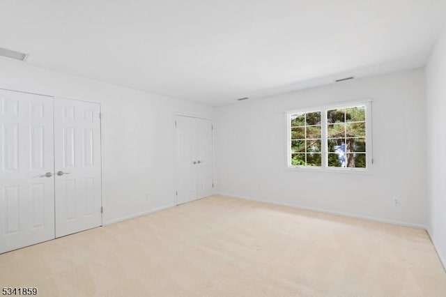 unfurnished room with carpet, visible vents, and baseboards