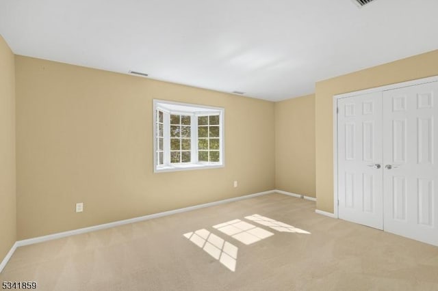 unfurnished bedroom with carpet floors, a closet, visible vents, and baseboards