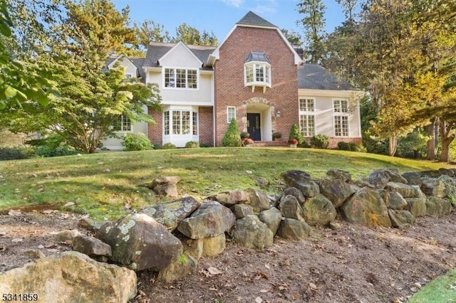 traditional-style home featuring a front lawn and brick siding