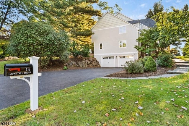 view of side of property featuring a garage, driveway, a yard, and stucco siding