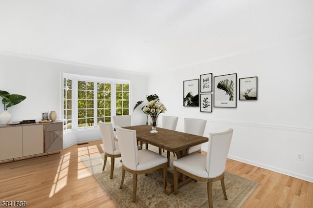 dining area with light wood-type flooring, baseboards, and ornamental molding