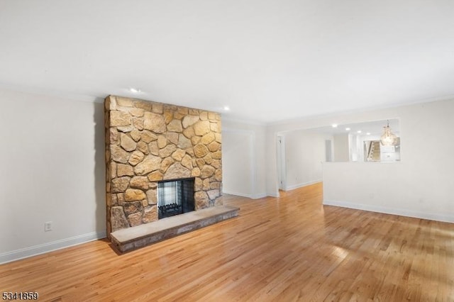 unfurnished living room with crown molding, a fireplace, wood finished floors, and baseboards