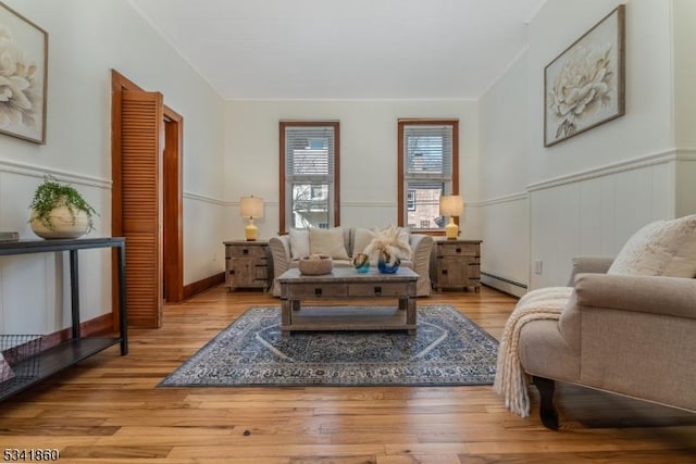 living room featuring a baseboard heating unit, wood finished floors, and wainscoting