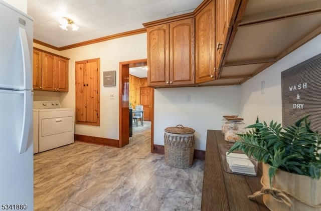 kitchen with washer / dryer, brown cabinets, crown molding, and freestanding refrigerator