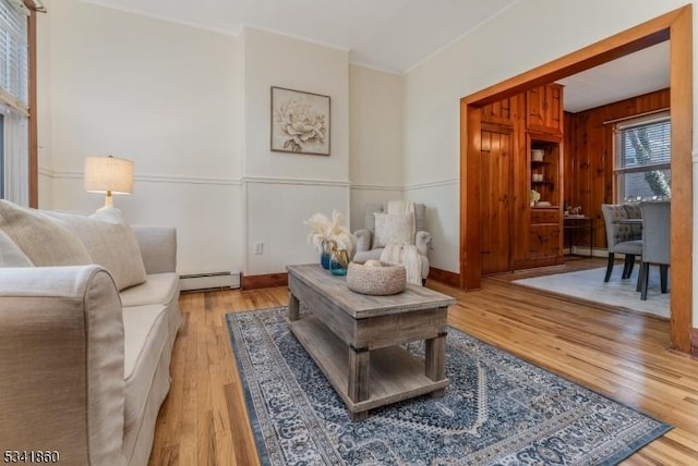 living area featuring crown molding, baseboard heating, and light wood-style floors