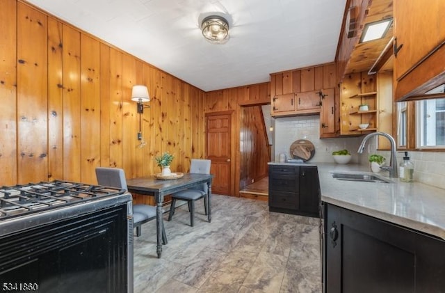 kitchen featuring a sink, light countertops, tasteful backsplash, brown cabinetry, and gas range