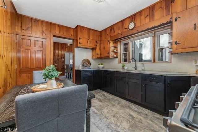 kitchen with wood walls, a sink, light countertops, dark cabinetry, and range