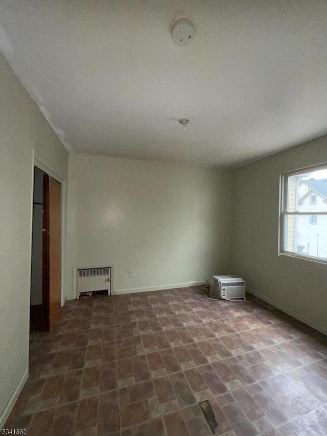 empty room with radiator heating unit and baseboards