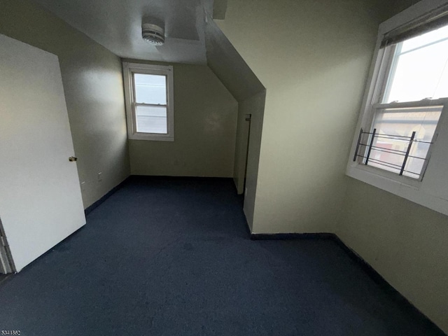 bonus room with vaulted ceiling, dark carpet, and baseboards